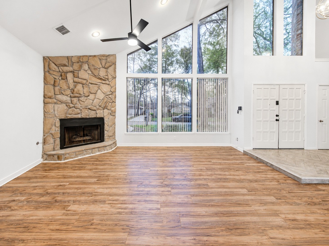 Double-height living room with stone fireplace and floor-to-ceiling windows